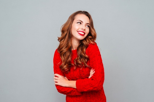 lachende vrouw in rode wollen trui is blij dat ze kleurrijk is gekleed voor haar date