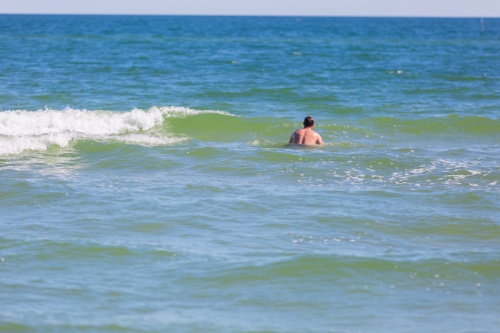 man zwemt naakt in zee terwijl zijn verwarde date nog op het strand staat