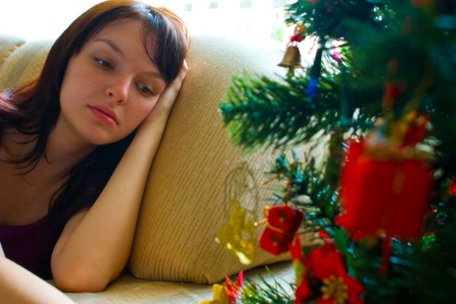 vrouw bij kerstboom is verdrietig want ze is alleen